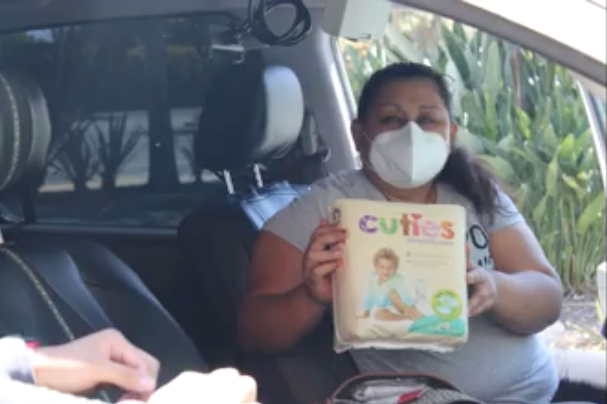a mom in a car holds a package of diapers