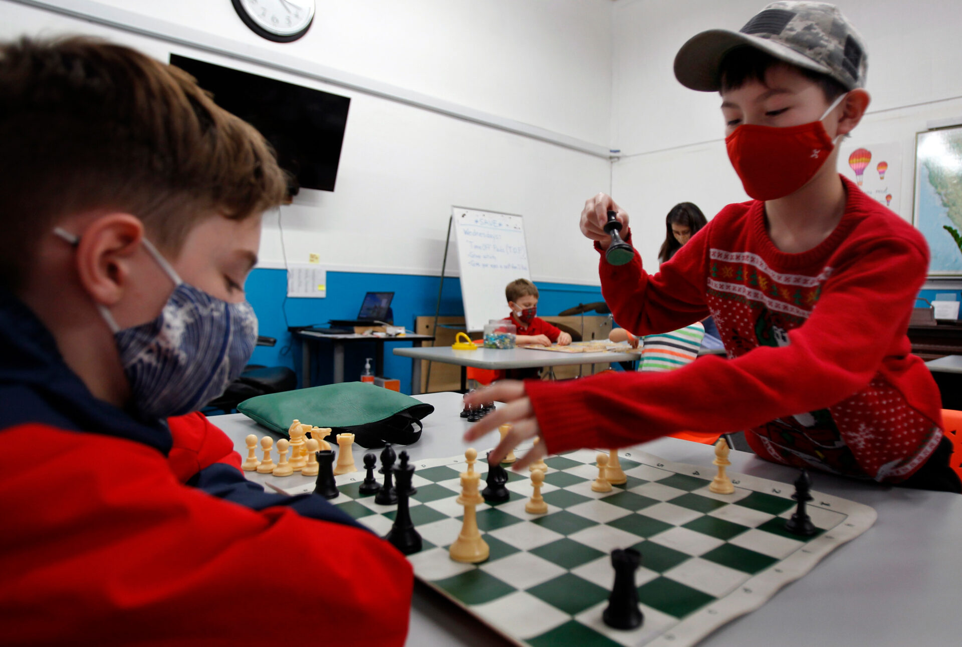 two children wearing masks play chess at a child care center