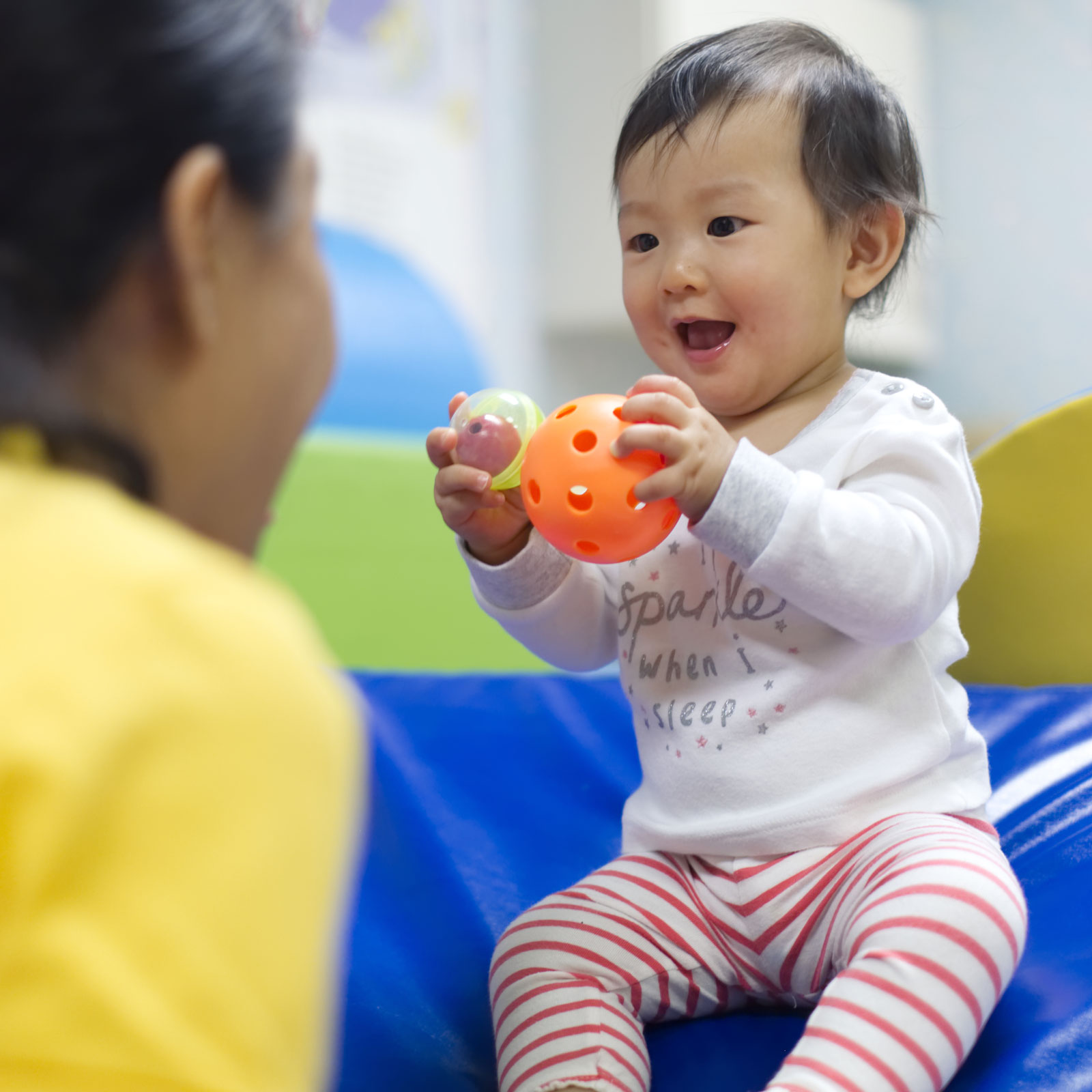 baby-holding-wiffle-ball Smiling baby holding a ball and looking at her mom