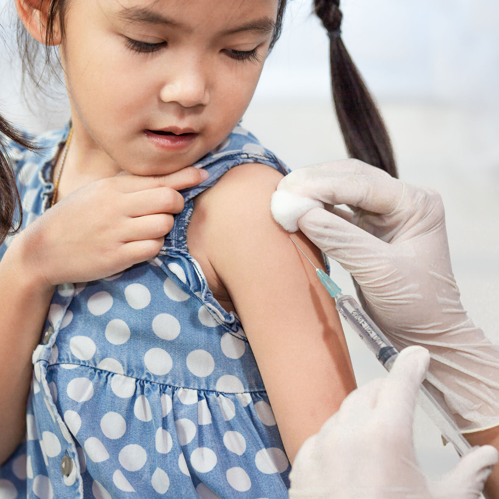 a young girl with pigtails gets a vaccine shot in her arm