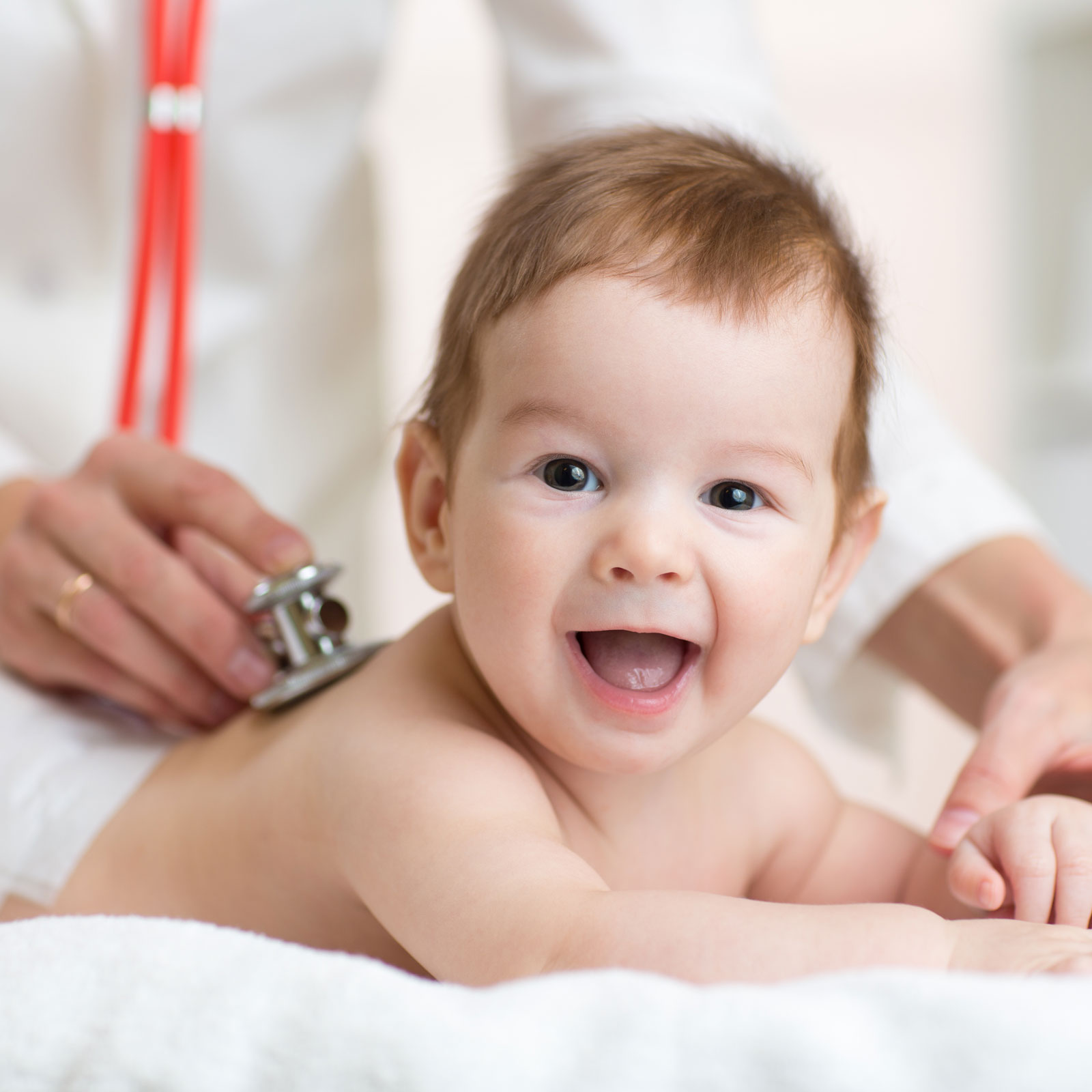 A pediatrician examines a happy baby with a stethoscope
