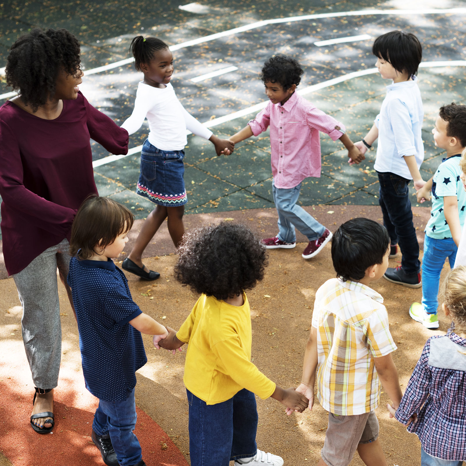 school-kids-circle children with their teacher in a circle playing a game on the blacktop at school